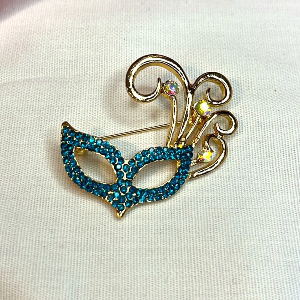 Brooch-eye mask shape, NIB, golden plumes off of one side. 1.5x1.5”, rhinestones